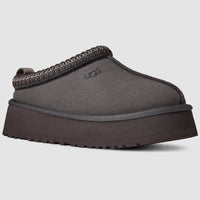 Gray UGG slipper with brown trim on a light gray background