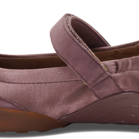 A single women's Mary Jane flat shoe in a dusty mauve-purple suede-like material, featuring a hook-and-loop strap closure, a brown sole, and a white heel insert with a partial visible 'ch' logo.