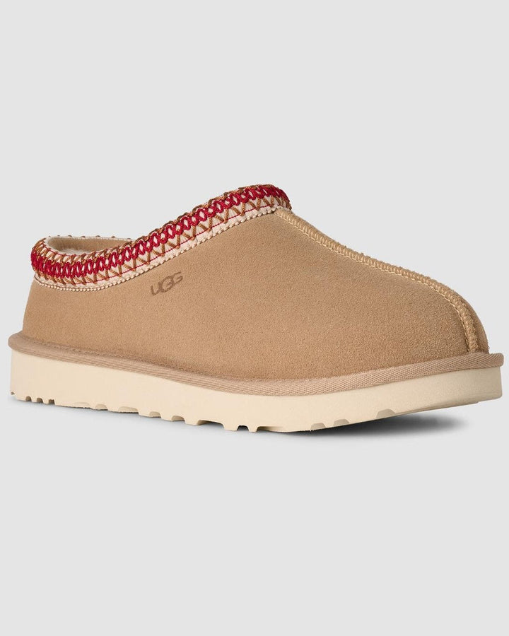 Tan slipper with red interior trim on a light gray background