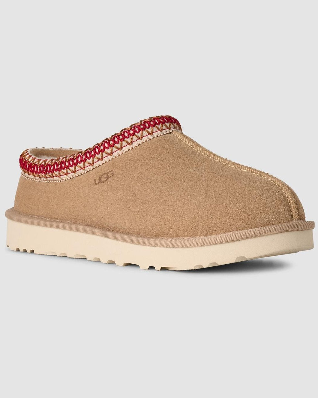 Tan slipper with red interior trim on a light gray background