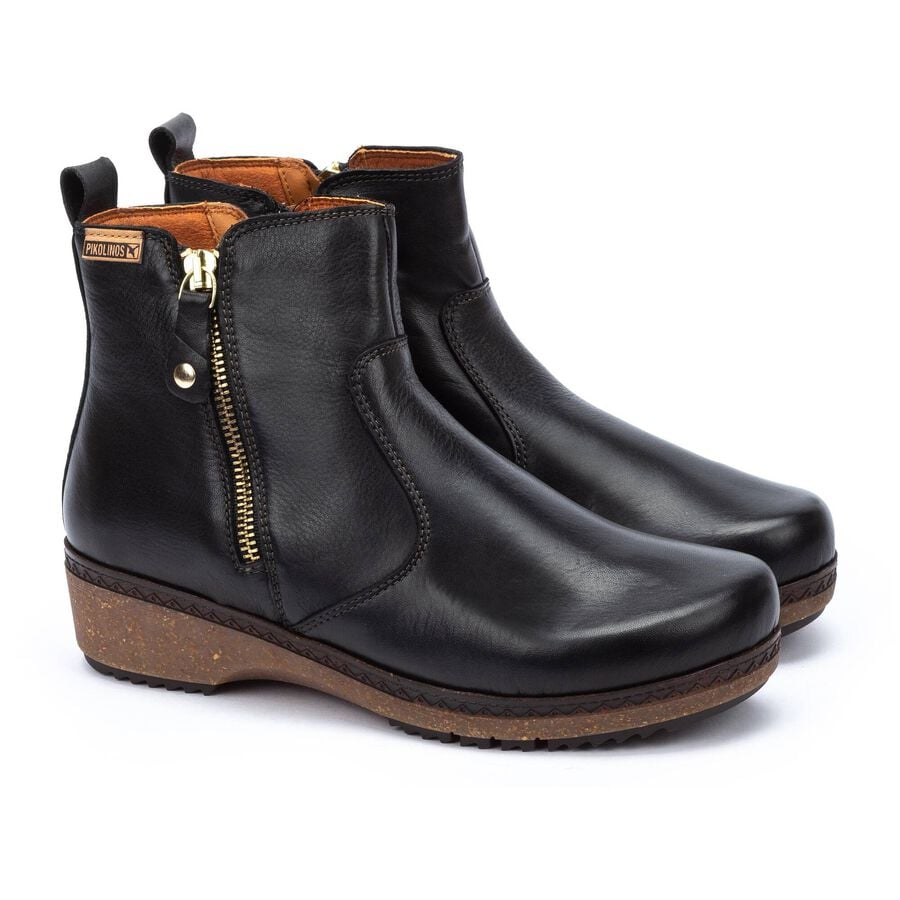 Pair of black leather ankle boots with a gold zipper on a white background