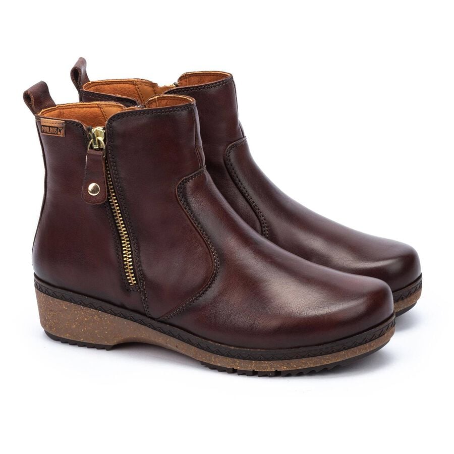 Pair of brown leather ankle boots with gold zippers on a white background