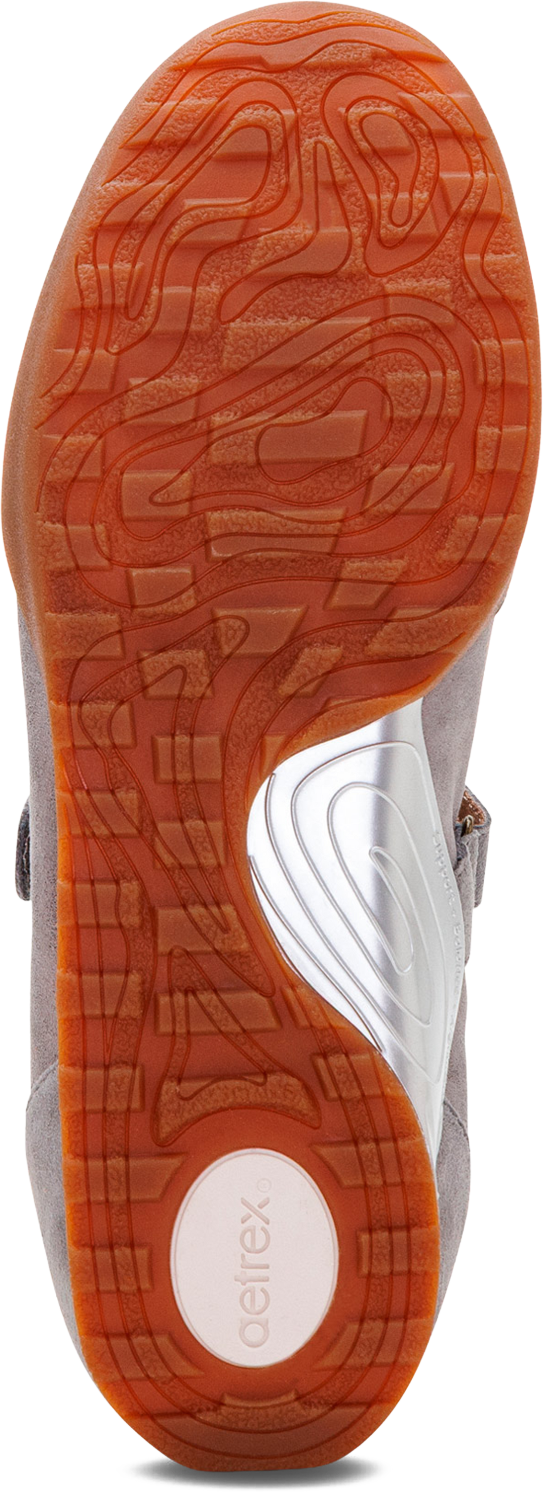 Close-up of the outsole of a sneaker, showing a textured orange rubber tread with a white circular logo area and the word &