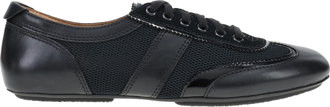 A black low-top sneaker with a mix of smooth leather and perforated mesh panels, featuring black laces and a black sole, shown from a side profile view on a white background.