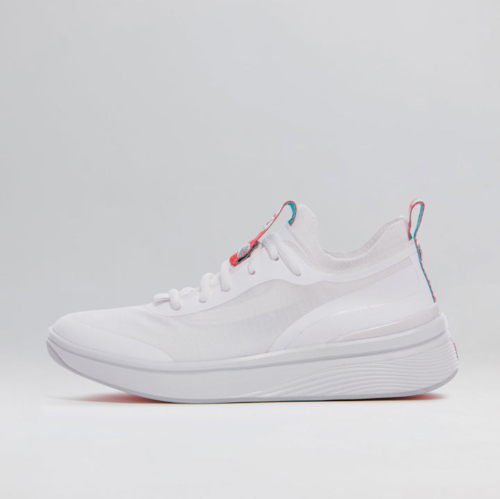 One of a pair of BALA Twelves in Flow White, which are bright white athletic-style sneakers for nurses and healthcare workers. It has white laces and bright red and sky blue details on the tongue and heel, and is photographed from the side against a white background.